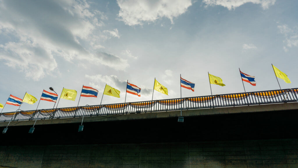 River cruise in bangkok, thailand with bangkok and thailand flags on the bridge